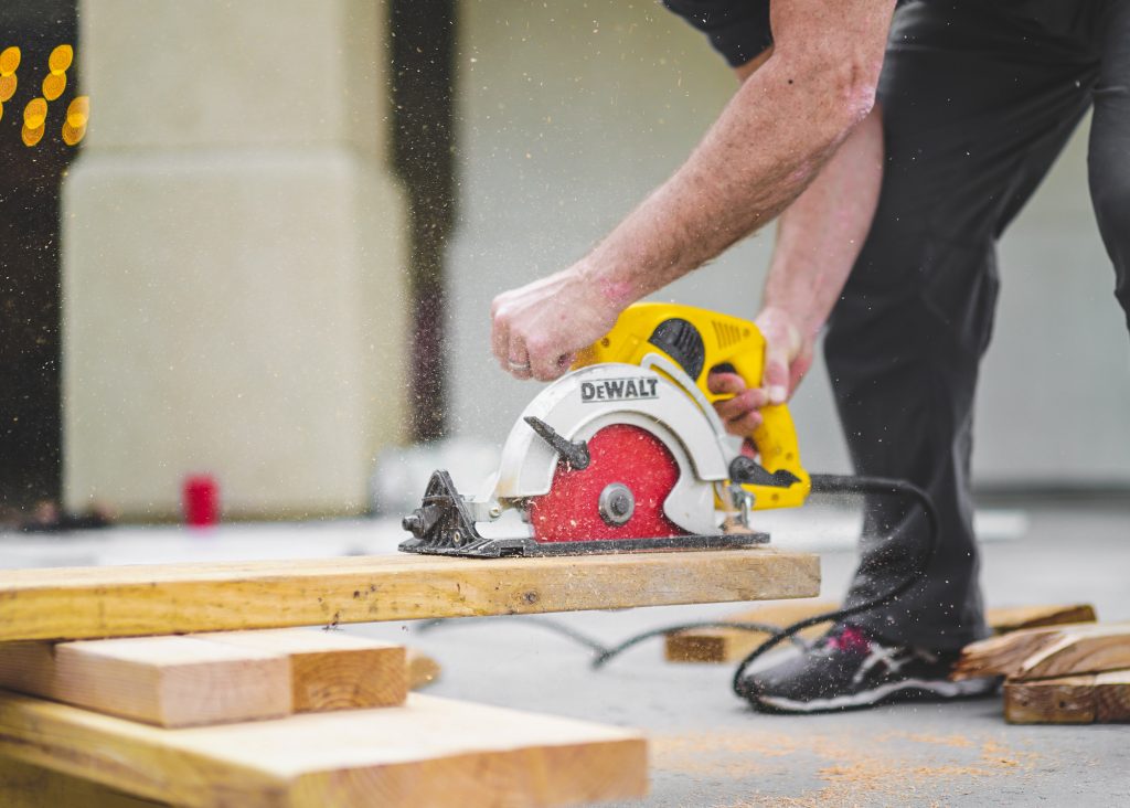 Man Using Dewalt Circular Saw On Plank Of Wood