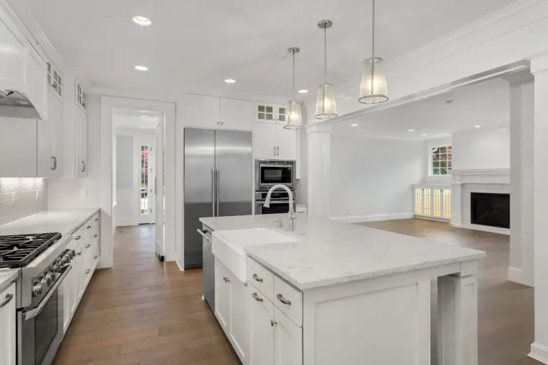 Bright, open-concept kitchen featuring a large center island, stainless steel appliances, and white cabinets