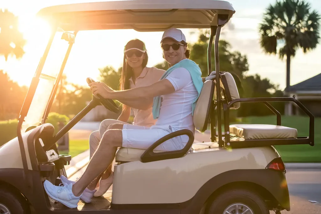 Smiling couple riding a golf cart at sunset in a Florida community
