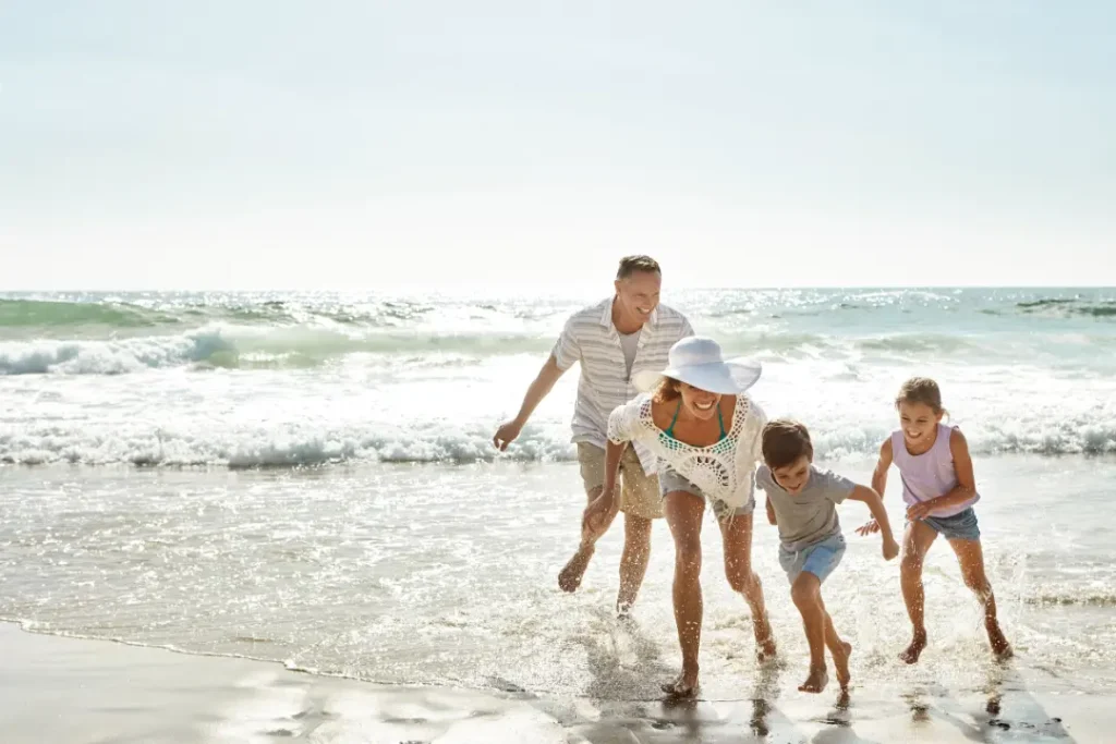 Family with two children running through shallow waves on a Florida beach