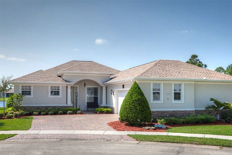 Exterior view of a single-story custom home with paver driveway in Vero Beach, Florida