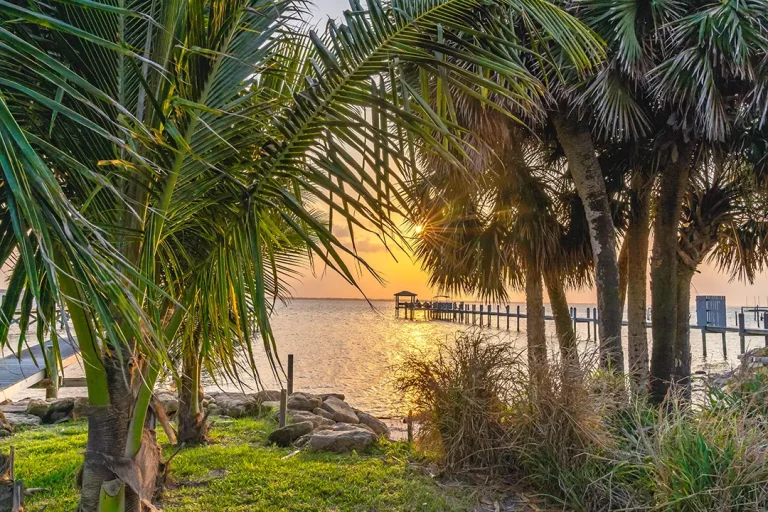 Waterfront view in Vero Beach, Florida with palm trees and dock at sunset