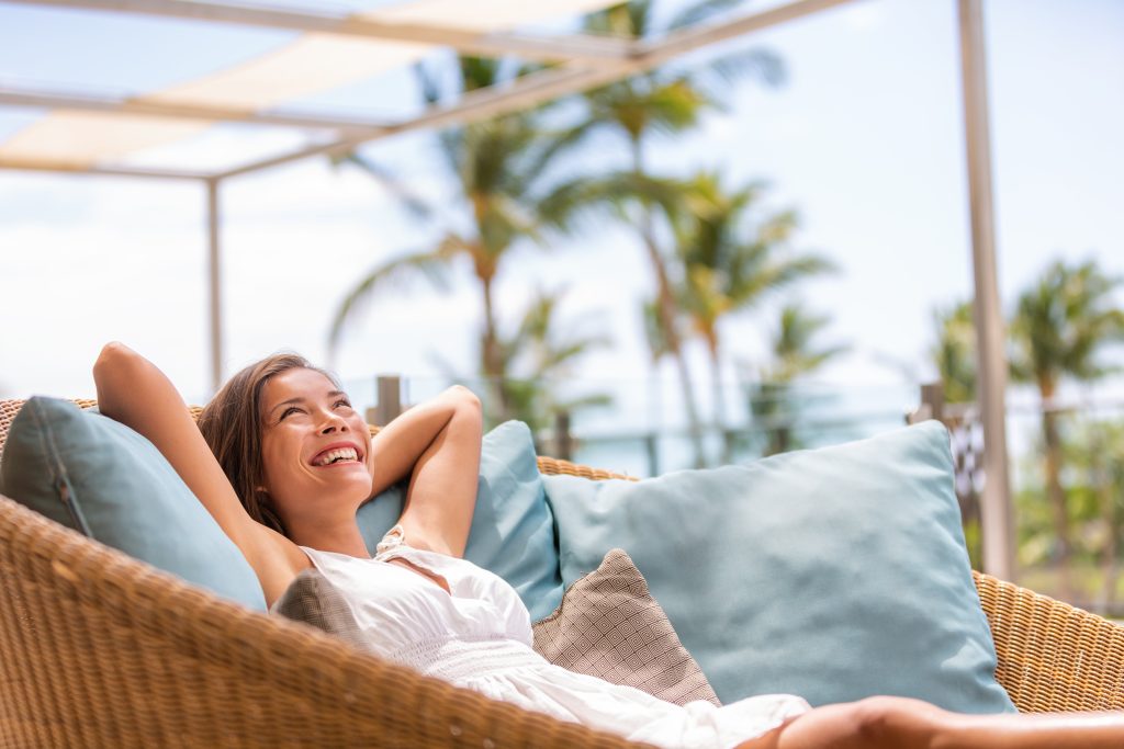 Smiling woman relaxing on an outdoor patio with palm trees in the background