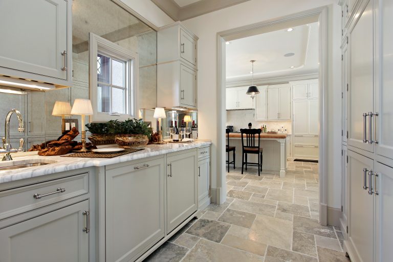 Butler’s pantry with custom cabinetry and marble countertop connecting to kitchen in a luxury Florida home
