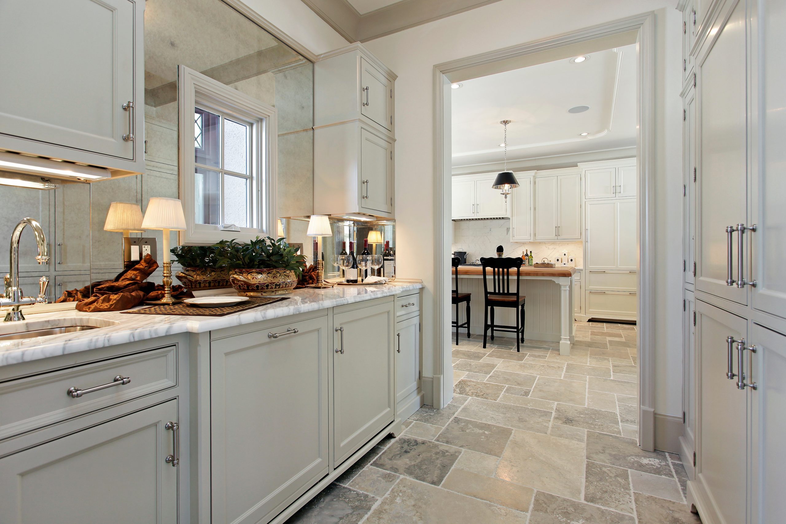 Butler’s pantry with custom cabinetry and marble countertop connecting to kitchen in a luxury Florida home